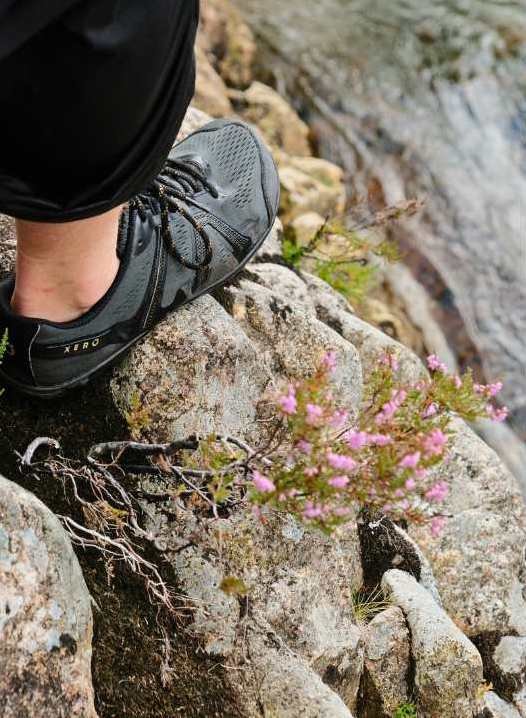 A man walking with Xero barefoot shoes on rocks