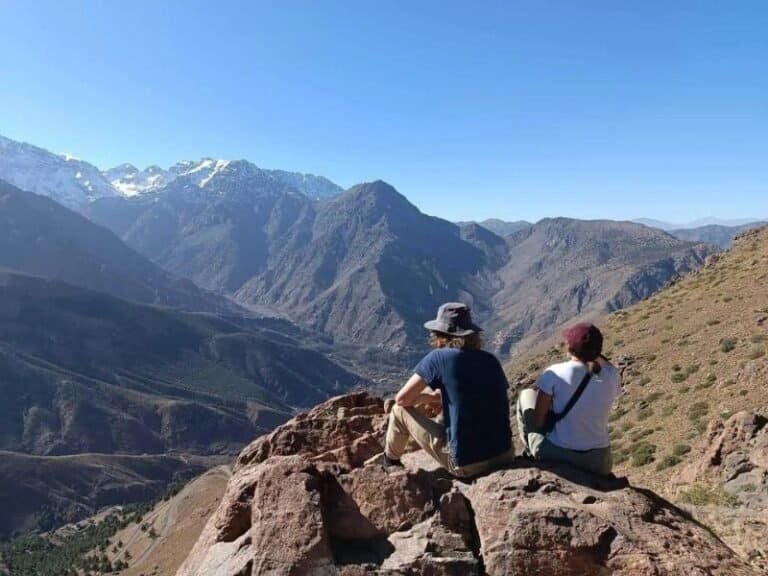 Hiking adventure in the mountains with two backpackers enjoying panoramic views, emphasizing outdoor exploration and travel experiences in remote destinations.