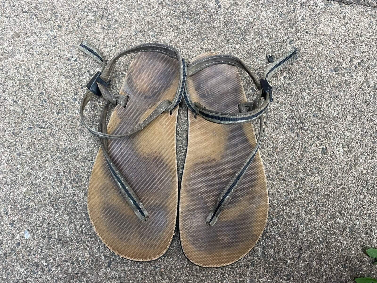 Worn-out sandals on a textured outdoor surface, ready for sustainable travel adventures.