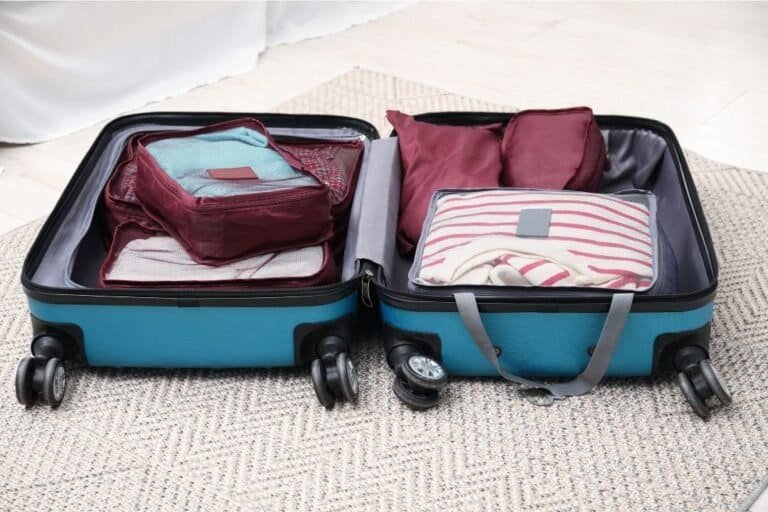 Clothes neatly packed inside a teal carry-on suitcase.