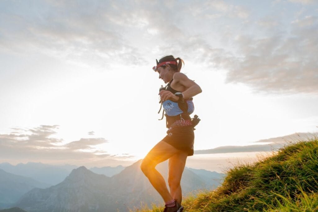 woman running during sunrise in mountain landscape, Eco-friendly outdoor activity, Sustainable travel, Grounded exploration for mindful adventurers.