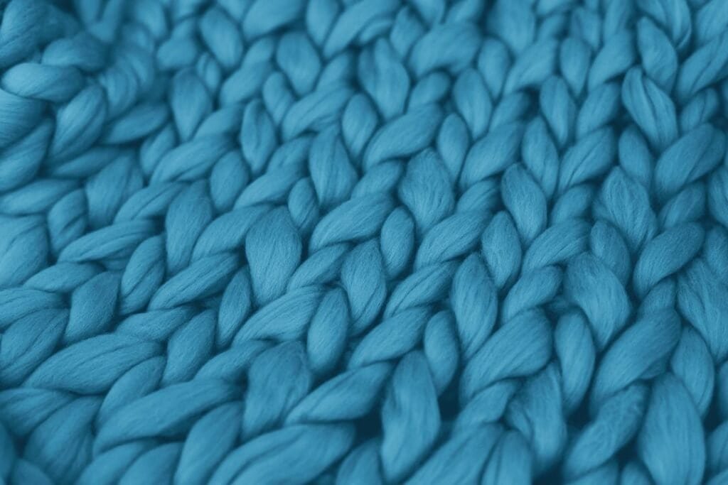 Thick, vibrant blue hand-knitted woolen yarn, close-up showing textured interwoven strands, perfect for sustainable, cozy crafts.