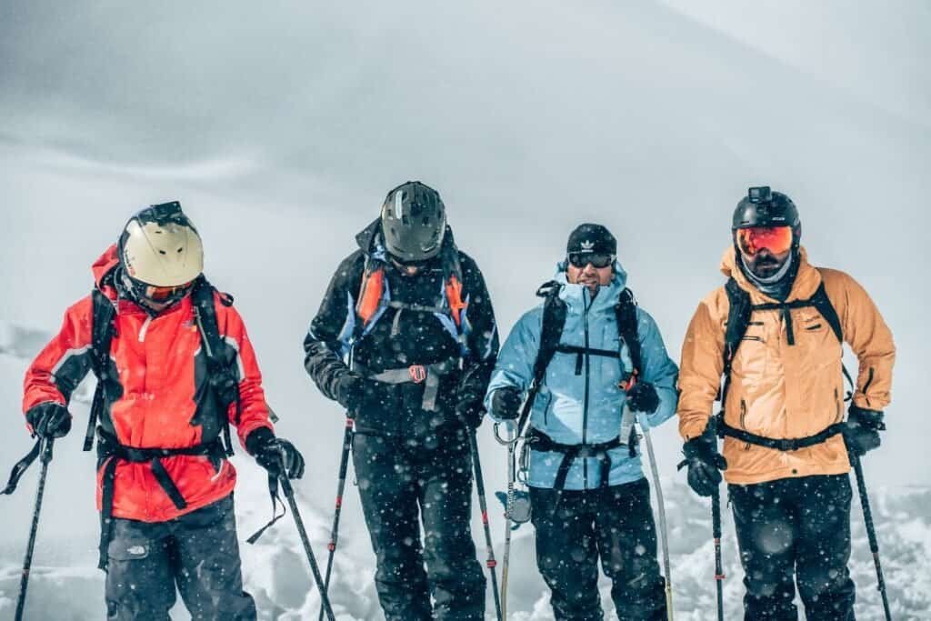Group of diverse hikers trekking in snowy mountains during winter, dressed in colorful outdoor gear, embracing sustainable adventure.
