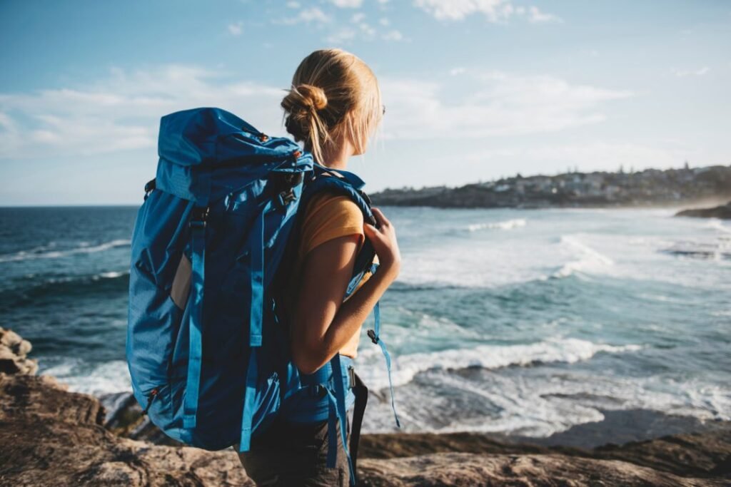 Perfect beachside hike with a backpacker with a 50l backpack for woman overlooking the ocean waves. Solo travel adventure emphasizing mindfulness and nature connection.