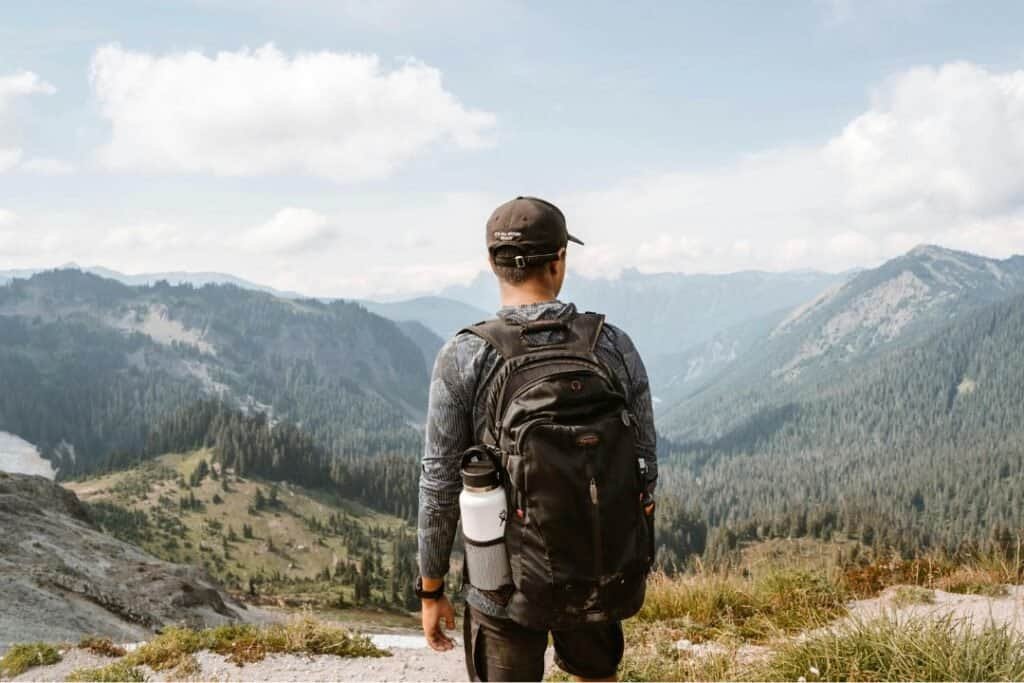 Hiking in Nature. A hiker with a backpack explores a lush mountain landscape, embracing mindful adventure and sustainable travel in pristine environments.