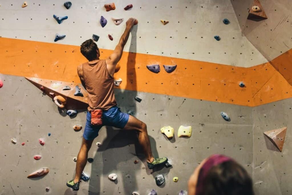 Climber reaching for holds on an indoor rock wall.