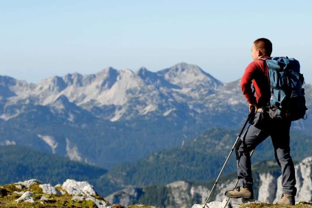 Majestic mountain hiker with backpack overlooking alpine landscape, embracing mindful adventure in nature.