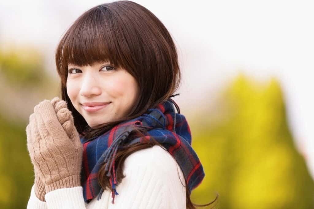 A young woman with brown hair and a checkered 100% Alpaca Wool Scarf enjoying a peaceful outdoor moment in nature.