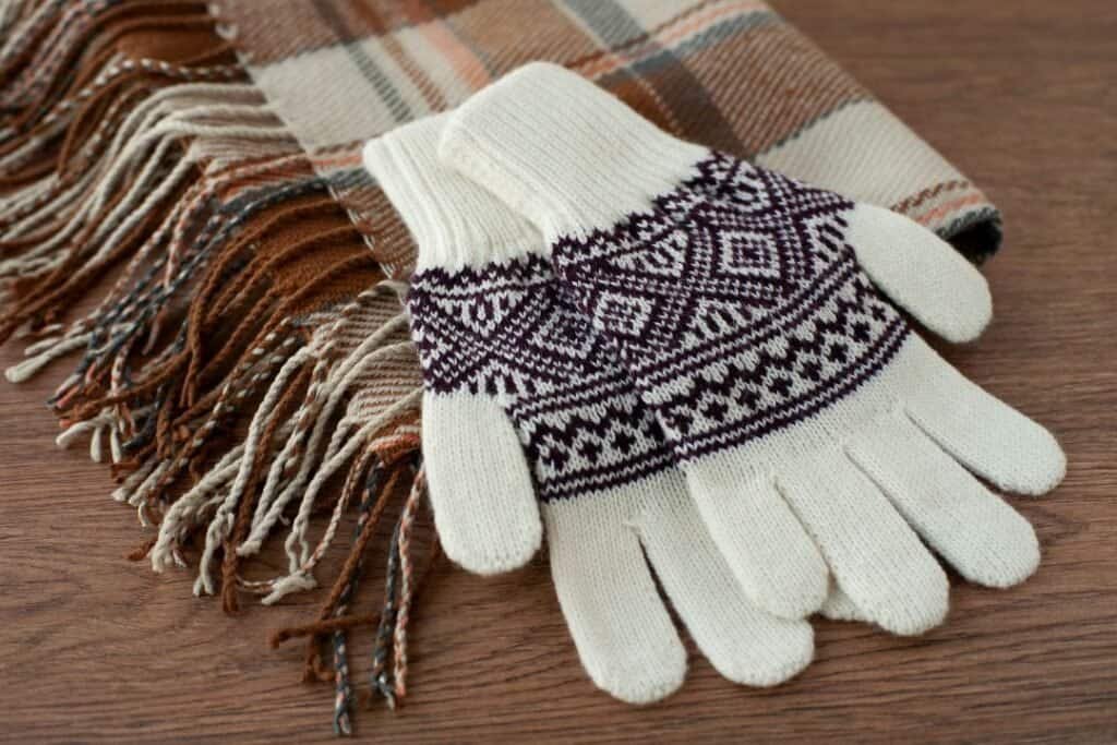 Warm Cashmere Gloves with Nordic pattern and soft scarf on wooden table for cozy, mindful winter travel.