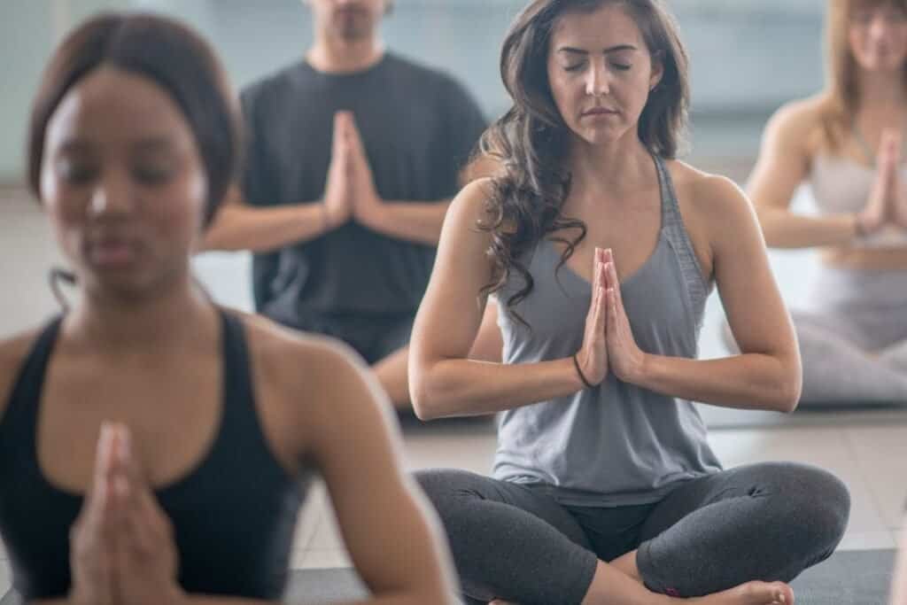Centered group of diverse people practicing mindfulness meditation in a peaceful indoor setting, promoting holistic wellness and sustainable living.