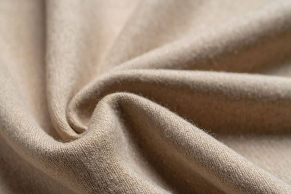 Soft beige linen fabric, emphasizing sustainable and natural cashmere sock materials for mindful living and grounded travel experiences.