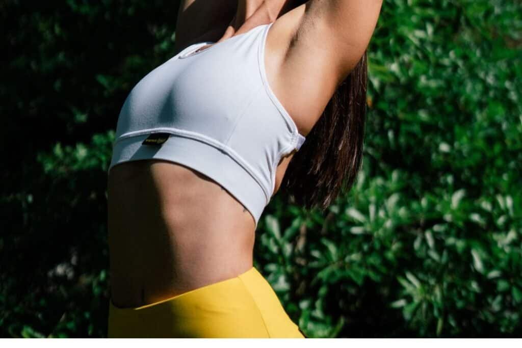 Bright yellow athletic wear under sunlight with lush green background, emphasizing mindful outdoor activity and sustainable active living.