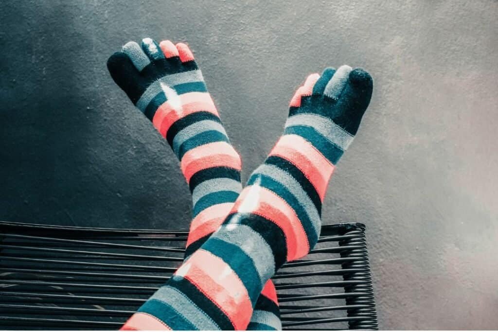 Colorful striped Toe socks Merino wool, relaxing on a black metal bench, inspiring cozy, grounded moments in sustainable travel experiences.