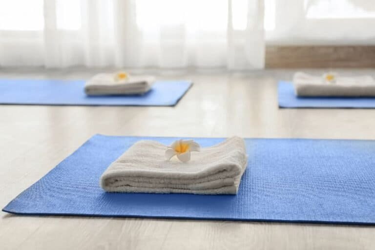 Folded white towels on blue yoga mats in a bright studio