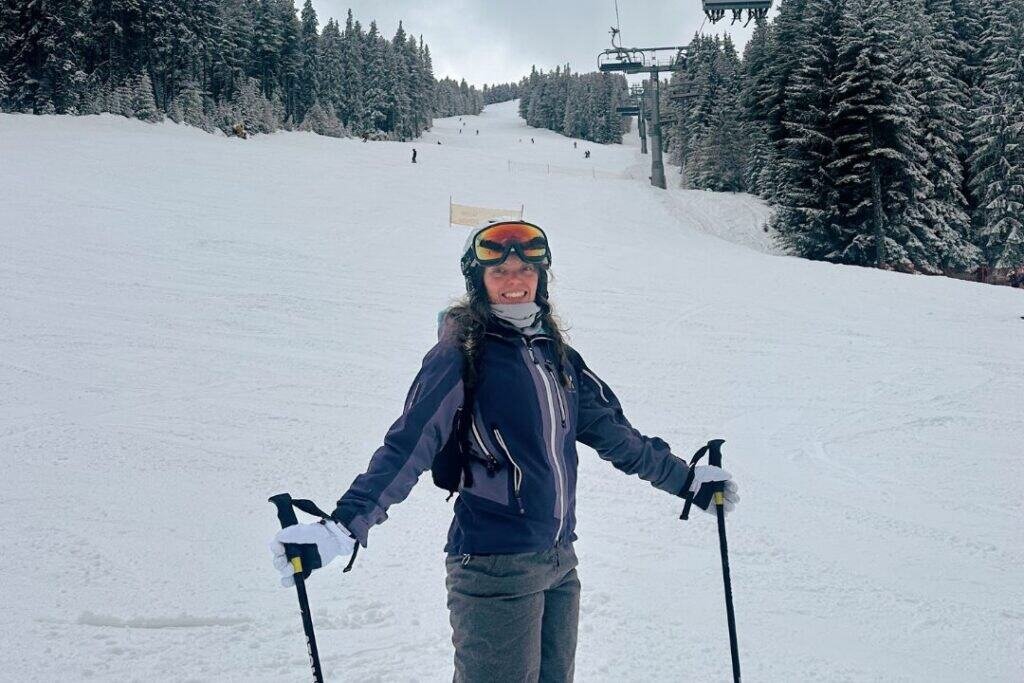 Enjoying a snowy mountain with a warm neck warmer landscape while skiing, surrounded by frosted pine trees under an overcast sky for a mindful winter outdoor adventure.