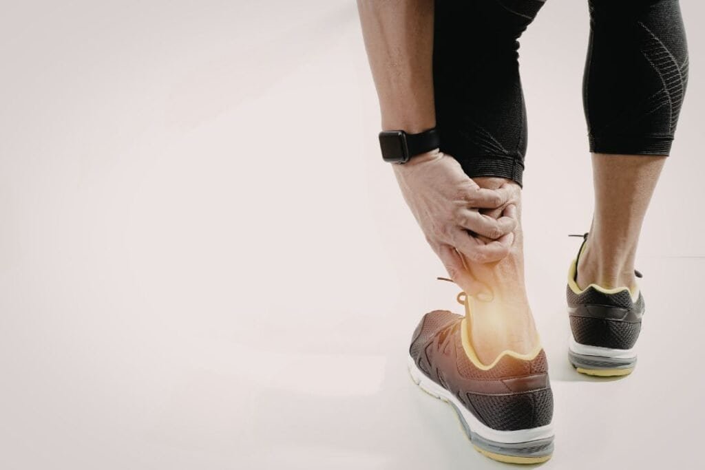 Achy ankle relief with person holding their ankle in supportive athletic footwear, highlighting injury prevention and mindful movement.