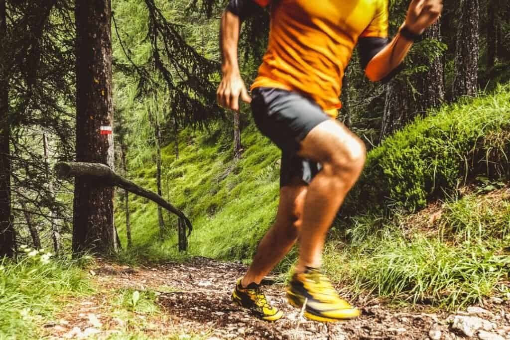 Running through lush forest trail in sustainable outdoor adventure gear for mindful exploration.