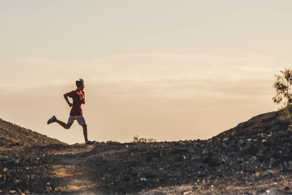 runner on a trail during sunset in a desert landscape, promoting mindful, sustainable outdoor adventures.