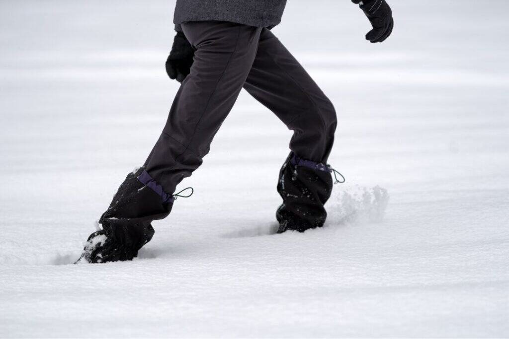 Cold weather snowshoeing in winter landscape, person walking through fresh snow on a snowy trail. Perfect for sustainable winter adventure and mindful travel.