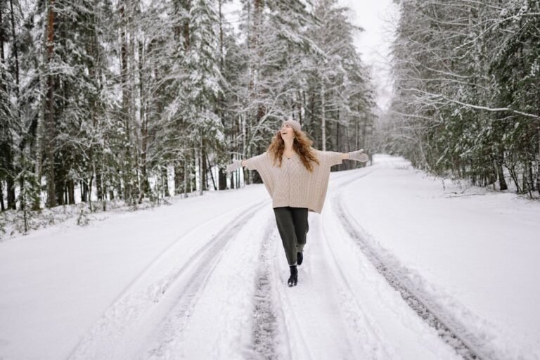 A woman walking a snowy forest trail in barefoot boots