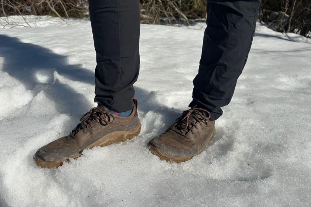 Grounded hiking shoes with wide toe box on snow, emphasizing comfort and connection to nature for mindful explorers.