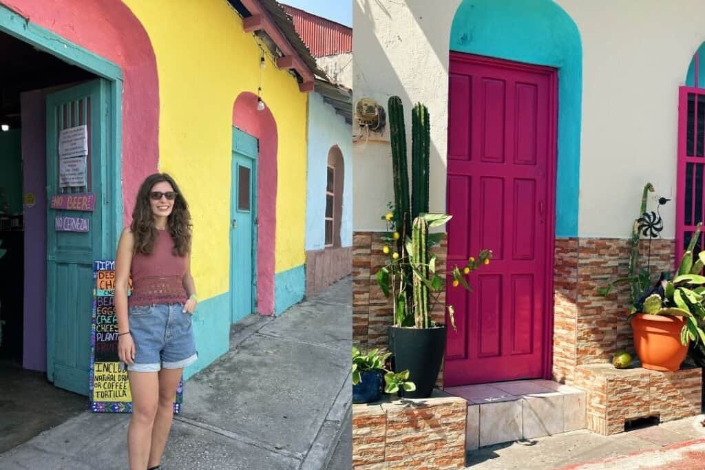 A colorful street scene with a woman standing in front of vibrant, painted buildings featuring bright pink, yellow, and turqu.