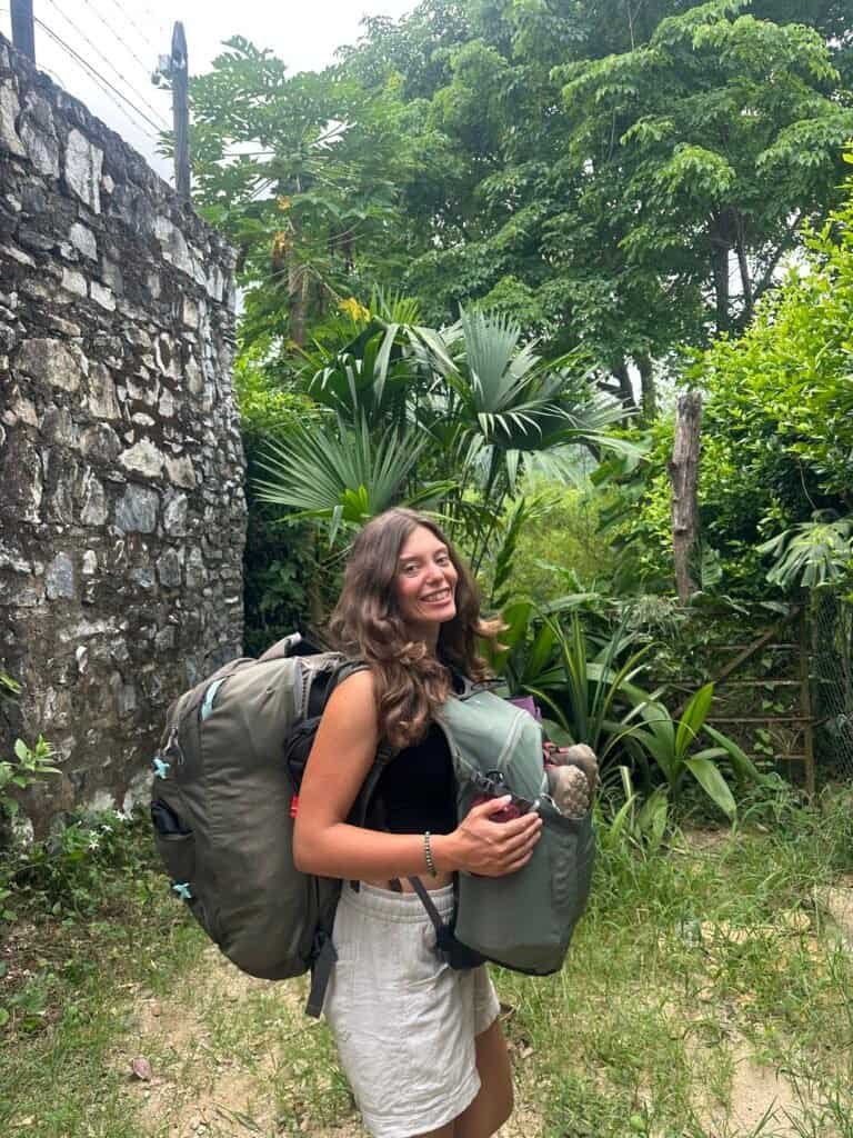 Ellen with a travel backpack and daypack on a green jungle path